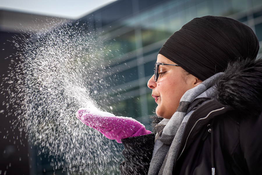 Student blows snow from her hand