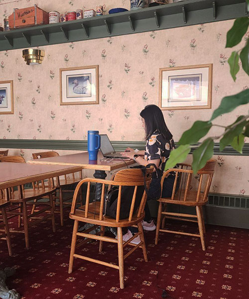 a woman sits at a table in an empty restaurant working on a laptop