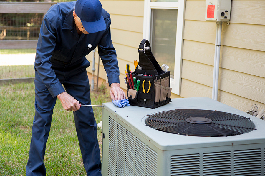 technician doing maintenance on an air conditioner unit outside