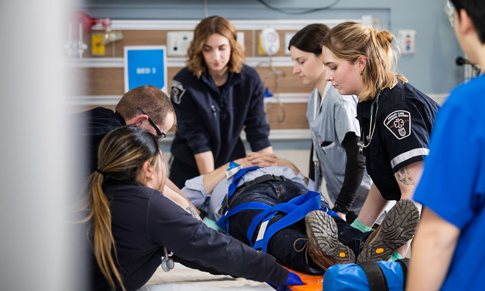 nait health care students transfer a patient to a hospital room during a medical simulation exercise
