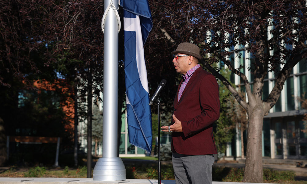 Derek Thunder, manager of the Nîsôhkamâtotân Centre at NAIT, speaks at the opening of the flagpole plaza