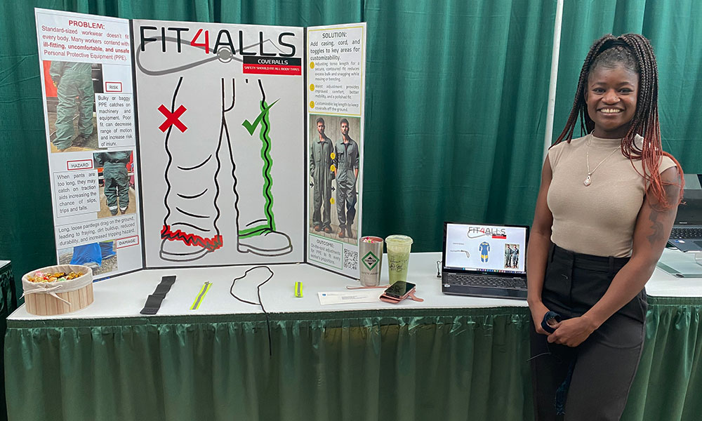 a woman in a tan shirt and black pants stands next to a poster board on a table that reads Fit4Alls