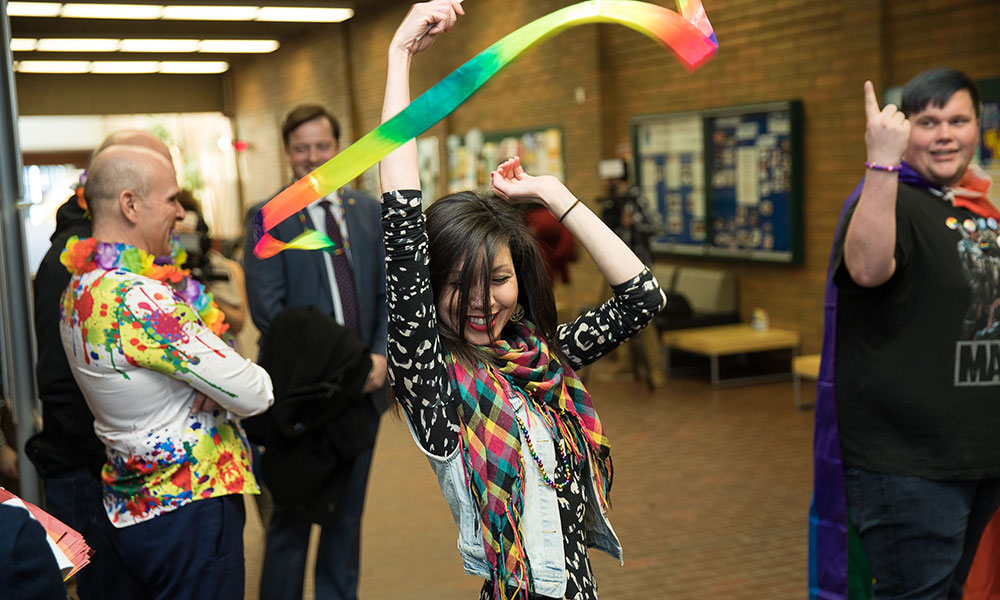 girl waving pride scarf at NAIT pride week