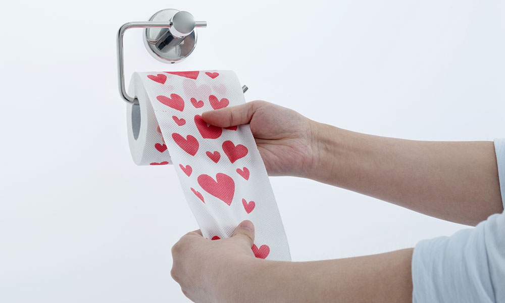 hands unrolling toilet paper with hearts on it
