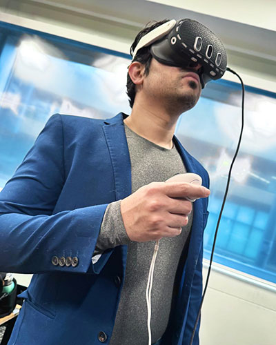 A person wearing a virtual reality headset holds a controller while standing indoors during a VR demonstration.