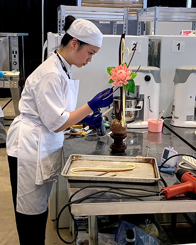 nait baking and pastry arts student judy lan working on a sugar sculpture