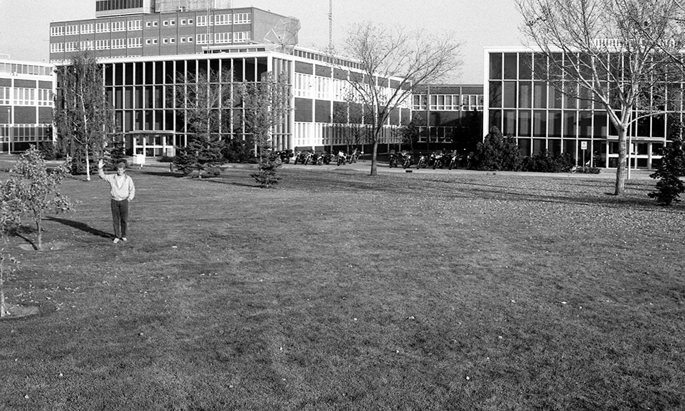 black and white photo of man waving from NAIT campus in the 1960s