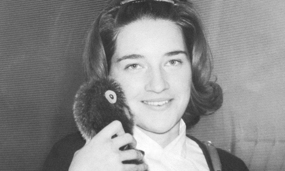 black and white photo of girl holding stuffed ookpik doll