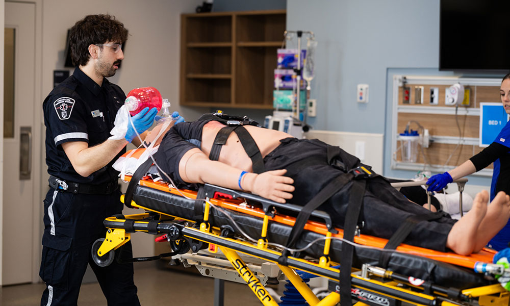 Medical emergency scene with a patient secured on a stretcher, receiving care from two healthcare professionals.