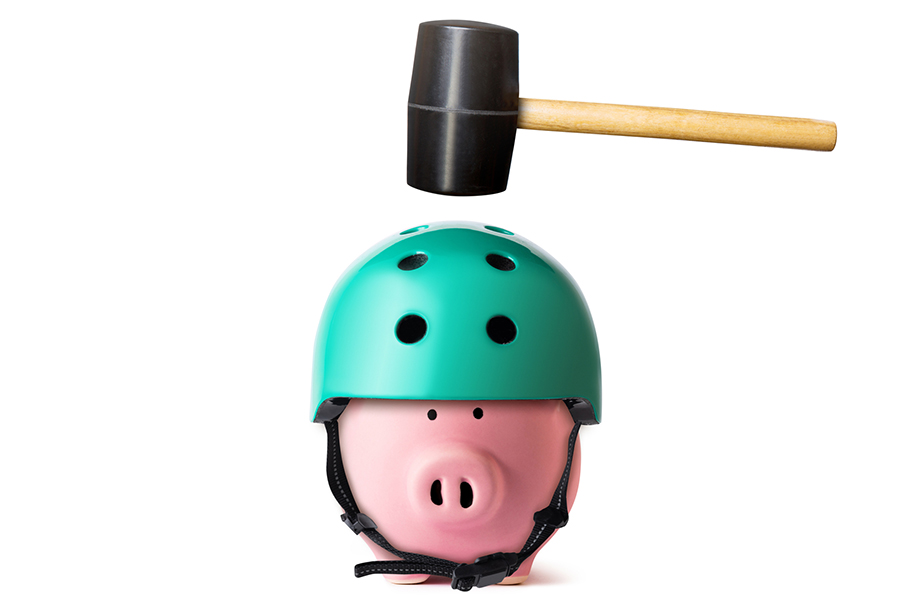 piggy bank wearing a helmet and about to be hit by a hammer
