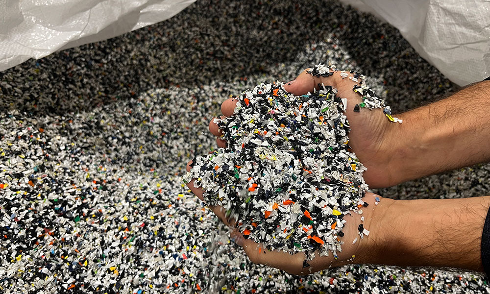 recycled plastic flakes in a large bag cupped in hands