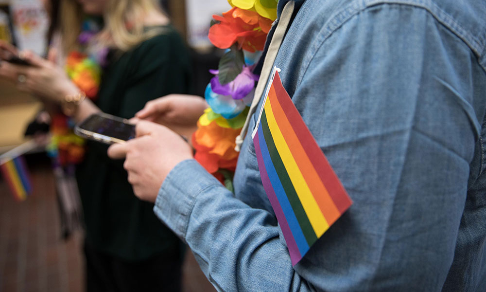photo of a pride flag in someone's arm while they use their phone