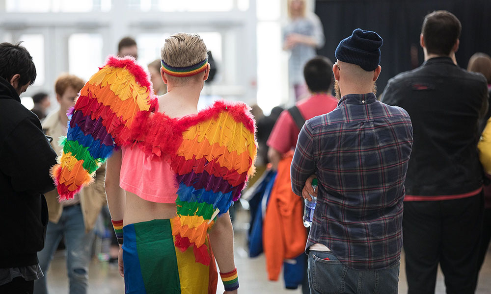 photo of two people watching a stage at NAIT, one wearing rainbow coloured wings