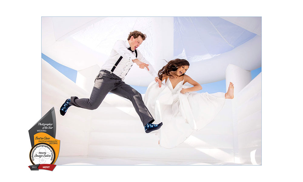 award-winning wedding photo by railene hooper featuring a bride and groom bouncing in a white inflatable