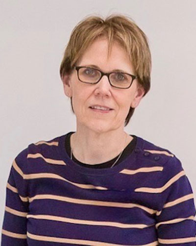 Upper‑body portrait of a person wearing a striped long‑sleeve top against a light, neutral background.