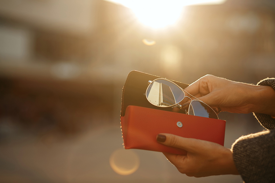 woman taking sunglasses out of case in the sunshine