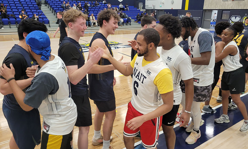 Players from two basketball teams line up on the court and exchange handshakes after a game.