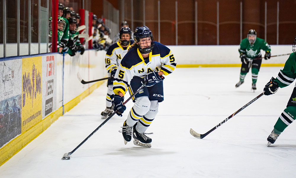 nait ooks women's hockey player takes the puck up the boards