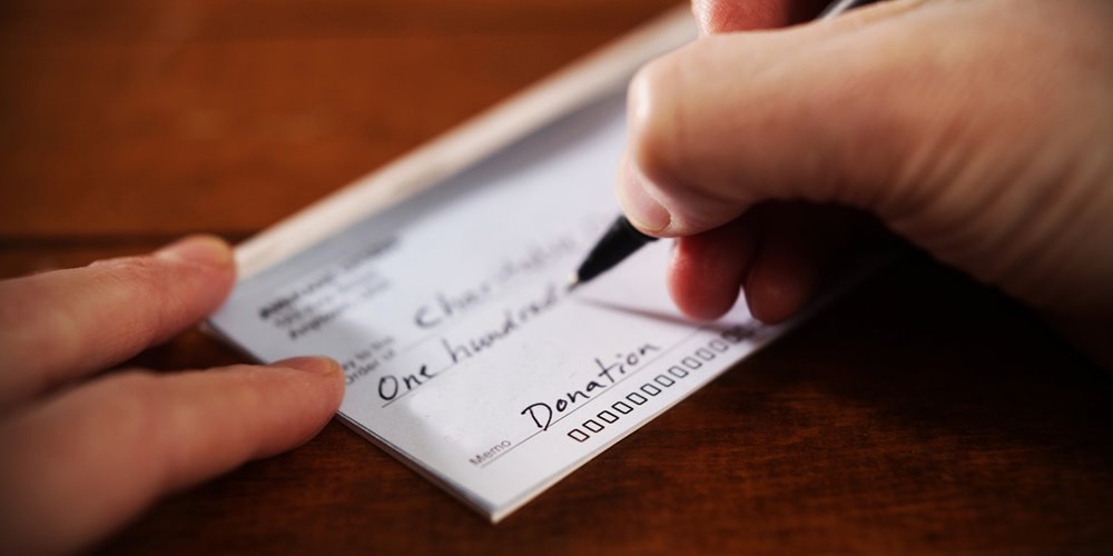 someone writing a cheque to make a donation