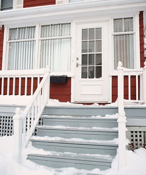 snow on stairs of a house with red siding and a porch
