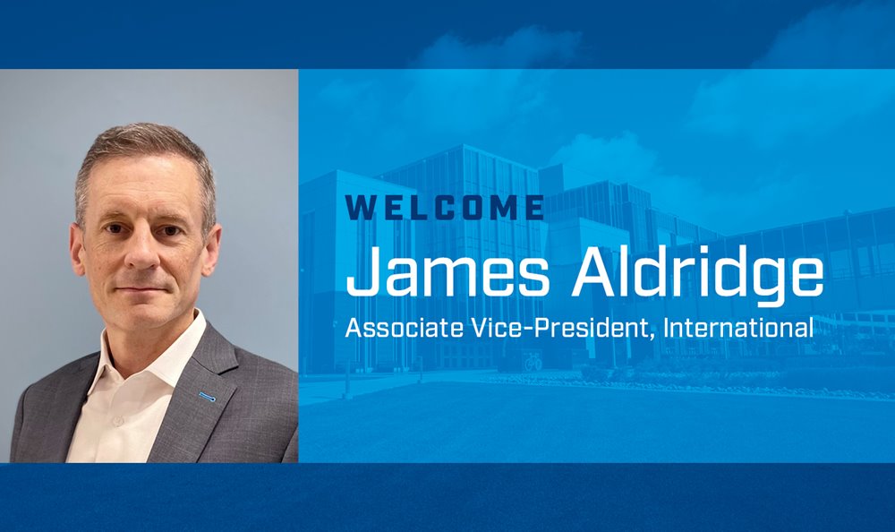 photo of a man with short grey-brown hair in a grey sport coat posing for a photo. to his right is a graphic that reads "welcome james aldridge"