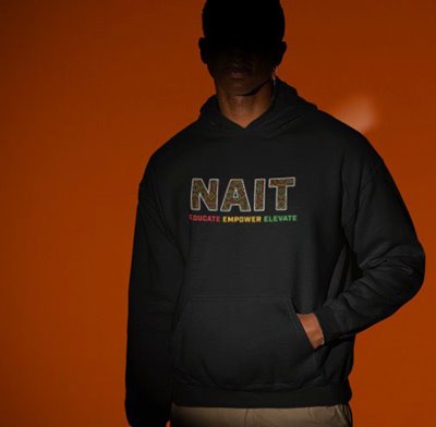 a model wears a sweater with the words NAIT, educate, empower, elevate on it. the model's face is shadowed. the background is organge.