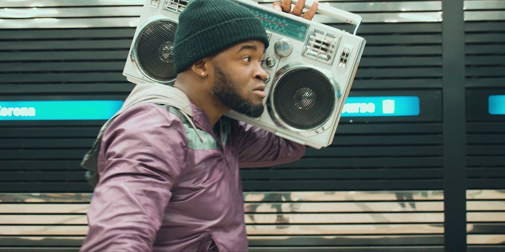 man holding beat box music player on shoulder as he walks