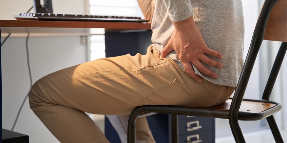 man sitting in chair with hand on his hip